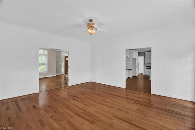 spare room featuring ornamental molding, a ceiling fan, wood finished floors, and baseboards