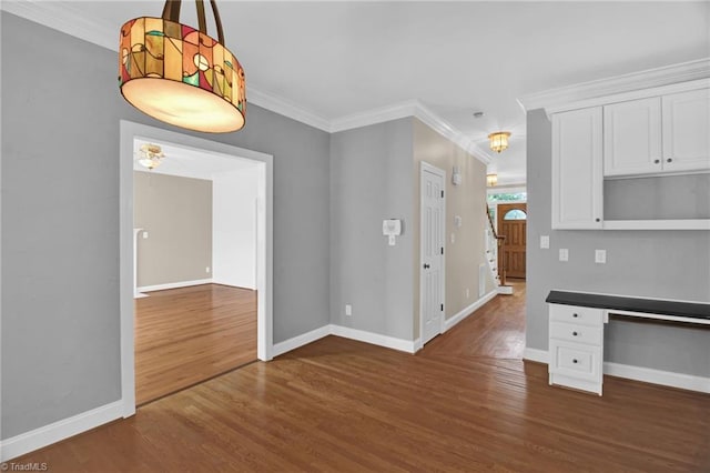 unfurnished dining area featuring dark wood-style floors, baseboards, and crown molding