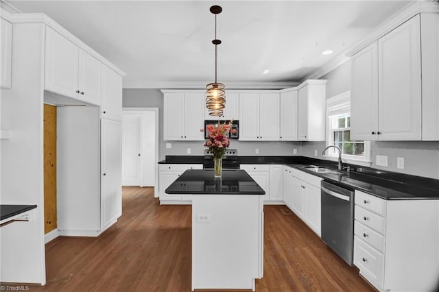 kitchen with appliances with stainless steel finishes, a sink, dark countertops, white cabinets, and ornamental molding
