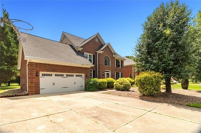 view of front of home with brick siding, an attached garage, concrete driveway, and a shingled roof
