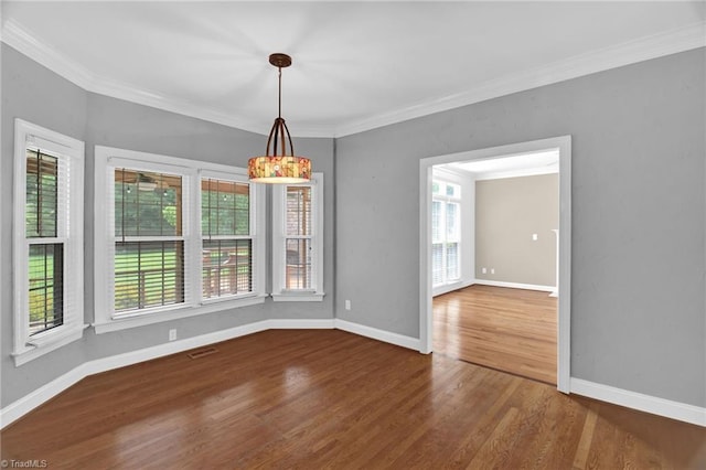 empty room with wood finished floors, baseboards, and crown molding