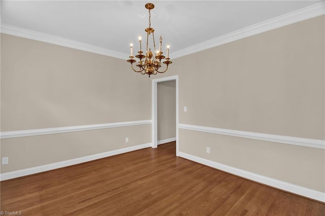 empty room featuring a chandelier, wood finished floors, baseboards, and crown molding