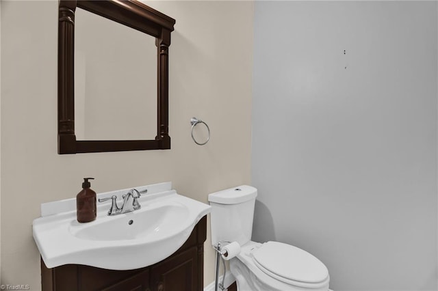 bathroom featuring toilet, vanity, and baseboards