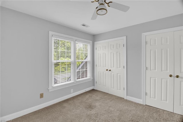 unfurnished bedroom featuring baseboards, carpet flooring, two closets, and ceiling fan
