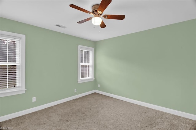 empty room with baseboards, carpet floors, ceiling fan, and healthy amount of natural light
