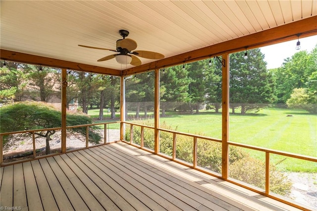 wooden deck with a ceiling fan, a yard, and view of wooded area