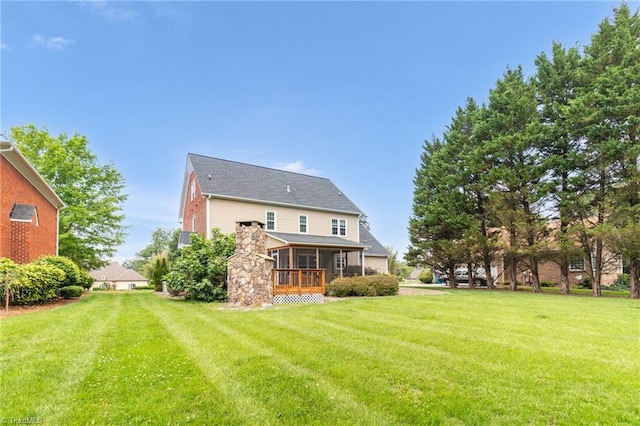 back of property featuring a sunroom and a yard