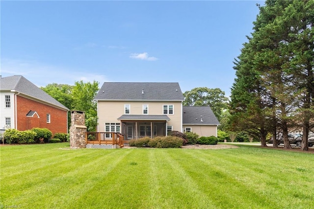 back of house featuring a sunroom, a lawn, and a wooden deck