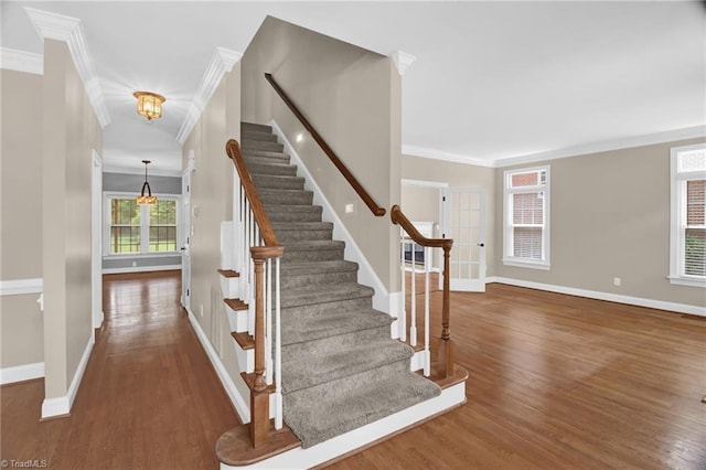 staircase with crown molding, baseboards, wood finished floors, and a chandelier