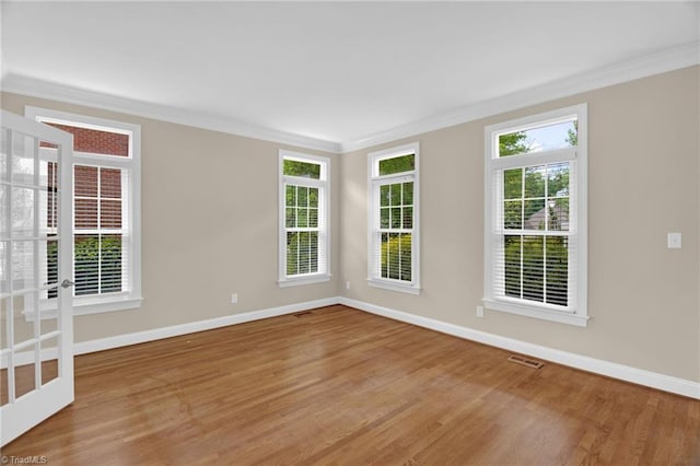 spare room with crown molding, wood finished floors, and baseboards
