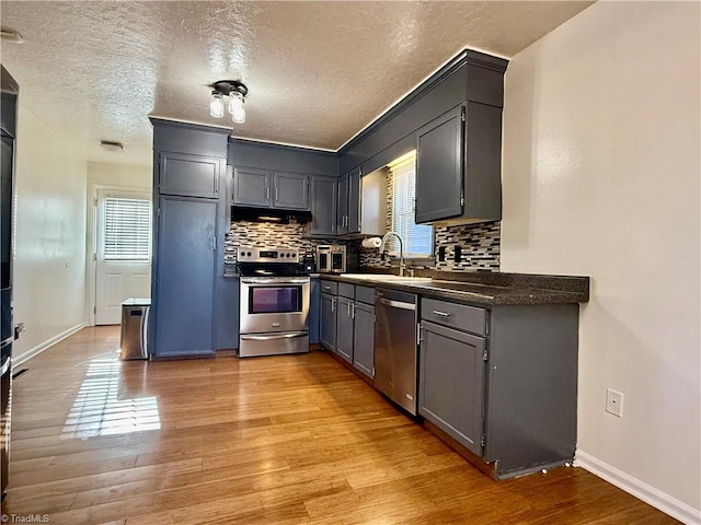 5314 Coble Church Rd, Julian, NC 27283 - kitchen featuring decorative backsplash, a sink, light wood finished floors, extractor fan, and appliances with stainless steel finishes