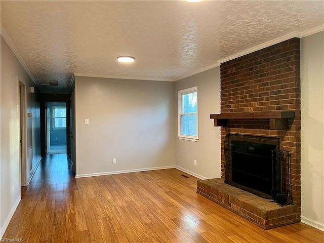 unfurnished living room featuring a brick fireplace, crown molding, hardwood / wood-style floors, and a textured ceiling