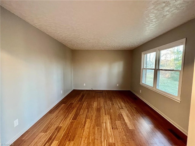 empty room featuring wood-type flooring and a textured ceiling