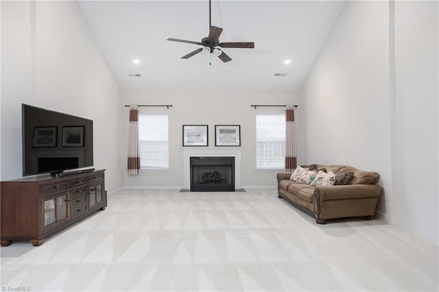 living area featuring plenty of natural light, visible vents, a fireplace with flush hearth, and light colored carpet