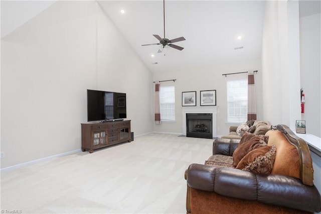 living area featuring light carpet, baseboards, high vaulted ceiling, and a fireplace with flush hearth