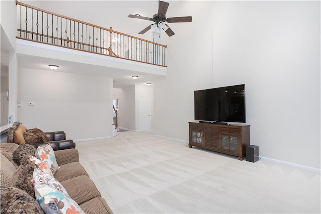 living area featuring ceiling fan, carpet, a towering ceiling, and baseboards