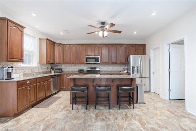 kitchen featuring a breakfast bar area, a center island, a sink, stainless steel appliances, and backsplash