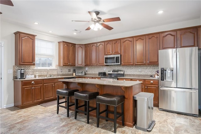 kitchen featuring a sink, a kitchen breakfast bar, appliances with stainless steel finishes, a center island, and tasteful backsplash