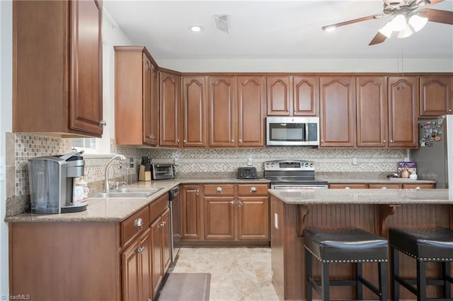 kitchen with tasteful backsplash, a breakfast bar area, light stone countertops, stainless steel appliances, and a sink