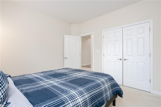 bedroom featuring light carpet, a closet, and baseboards