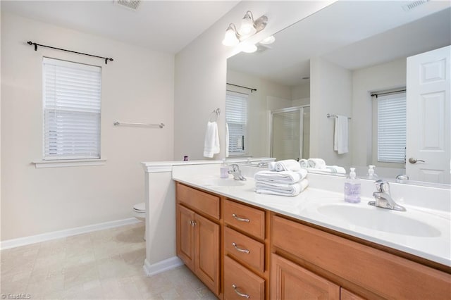 bathroom with a stall shower, a sink, baseboards, and double vanity