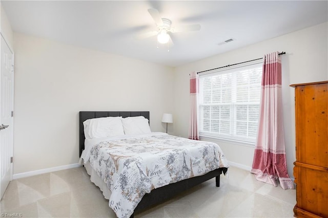 bedroom with a ceiling fan, visible vents, light carpet, and baseboards