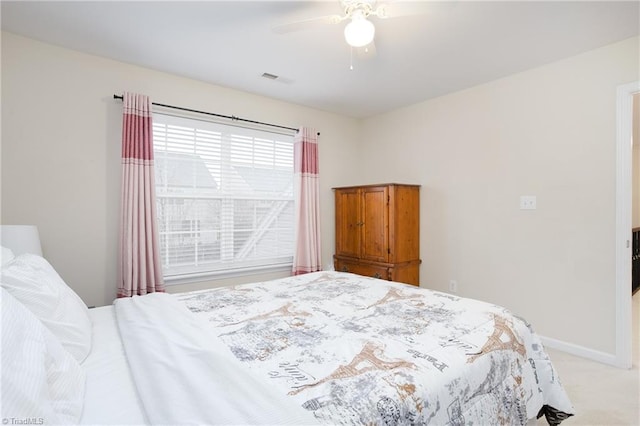 bedroom with light carpet, ceiling fan, visible vents, and baseboards