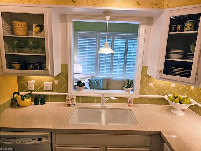 kitchen with tasteful backsplash, white cabinetry, sink, and white dishwasher