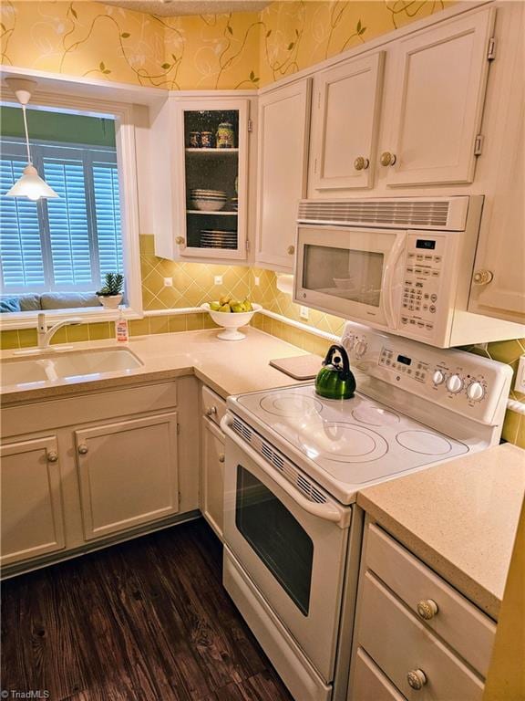 kitchen with dark hardwood / wood-style flooring, hanging light fixtures, sink, white cabinetry, and white appliances