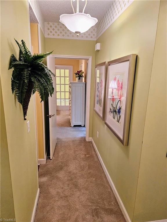 hallway featuring light colored carpet and a textured ceiling