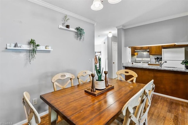 dining space featuring dark hardwood / wood-style flooring, sink, and crown molding