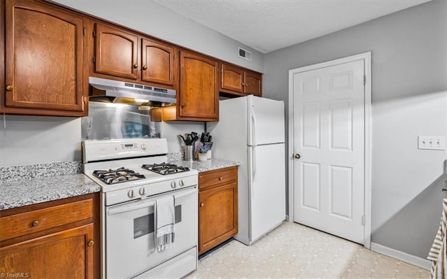 kitchen with white appliances, light stone countertops, and a textured ceiling