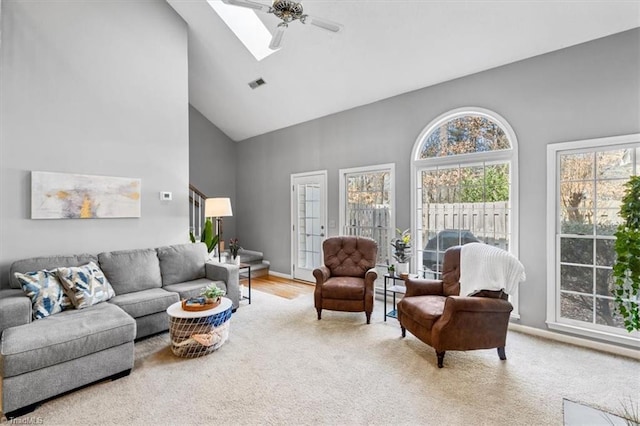 carpeted living room featuring ceiling fan, high vaulted ceiling, and a skylight