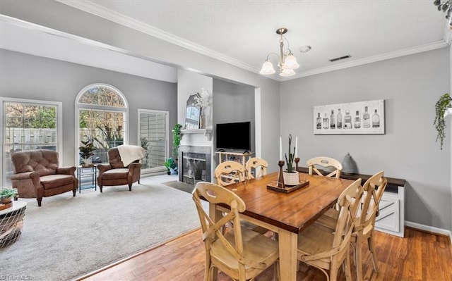 dining space with a notable chandelier, hardwood / wood-style flooring, and ornamental molding