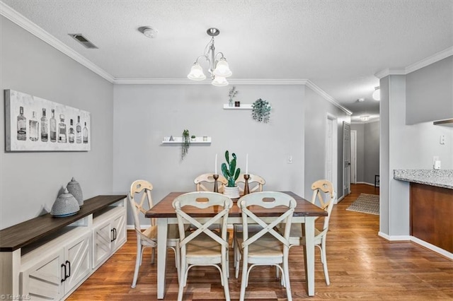 dining area featuring an inviting chandelier, crown molding, hardwood / wood-style floors, and a textured ceiling