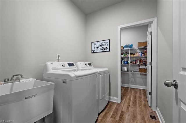laundry area with laundry area, wood finished floors, visible vents, a sink, and independent washer and dryer