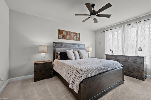 bedroom featuring light carpet, a ceiling fan, and baseboards
