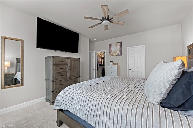 bedroom with a ceiling fan, a closet, a spacious closet, carpet, and baseboards