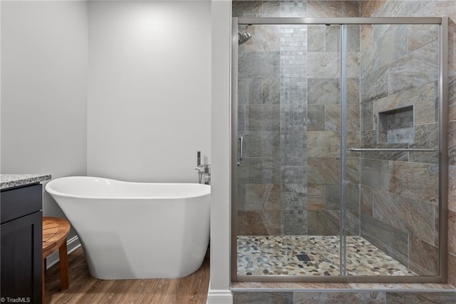 full bath with a soaking tub, wood finished floors, vanity, and a stall shower