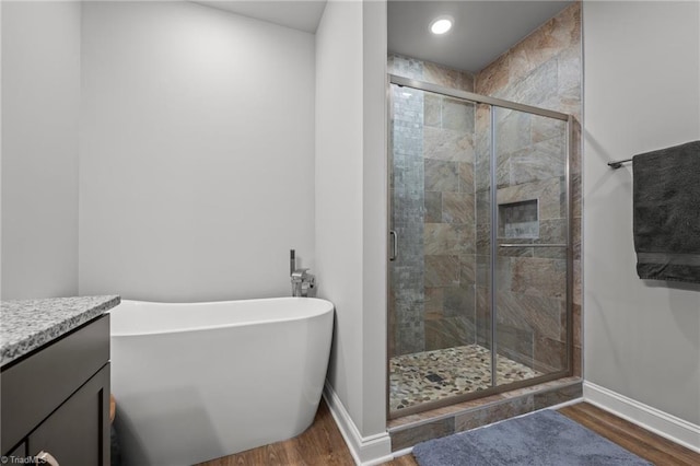 bathroom featuring a shower stall, baseboards, a freestanding tub, and wood finished floors