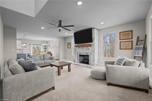 carpeted living area with ceiling fan with notable chandelier, plenty of natural light, a fireplace, and recessed lighting