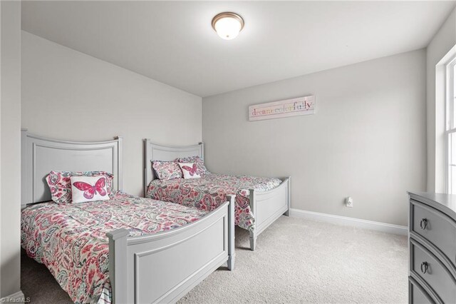 bedroom with light colored carpet and baseboards
