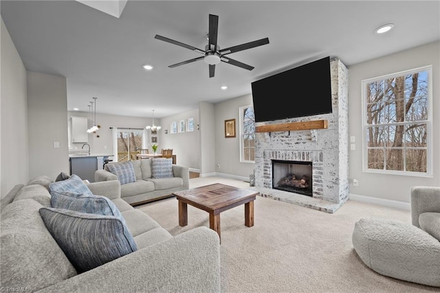 living room featuring ceiling fan with notable chandelier, a fireplace, baseboards, carpet flooring, and recessed lighting
