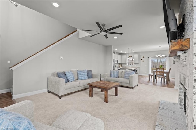 living area with recessed lighting, stairs, baseboards, light colored carpet, and ceiling fan with notable chandelier