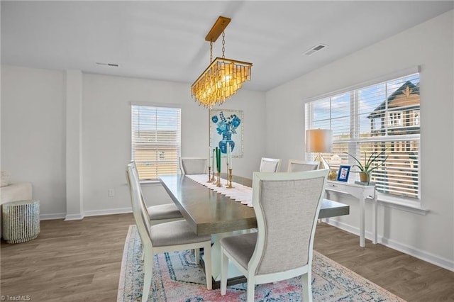 dining room featuring wood-type flooring, plenty of natural light, and an inviting chandelier