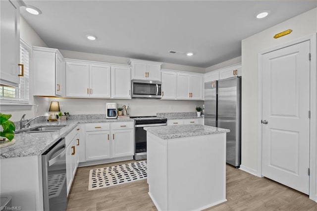 kitchen featuring sink, appliances with stainless steel finishes, light hardwood / wood-style floors, white cabinets, and a kitchen island