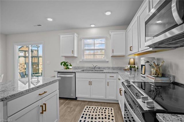 kitchen featuring sink, stainless steel appliances, a healthy amount of sunlight, white cabinets, and light wood-type flooring