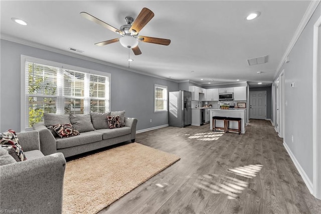 living room featuring crown molding, plenty of natural light, and hardwood / wood-style flooring