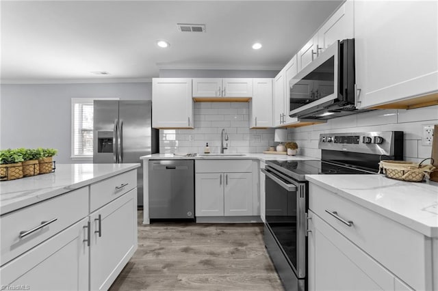 kitchen featuring stainless steel appliances, white cabinetry, sink, and light stone countertops