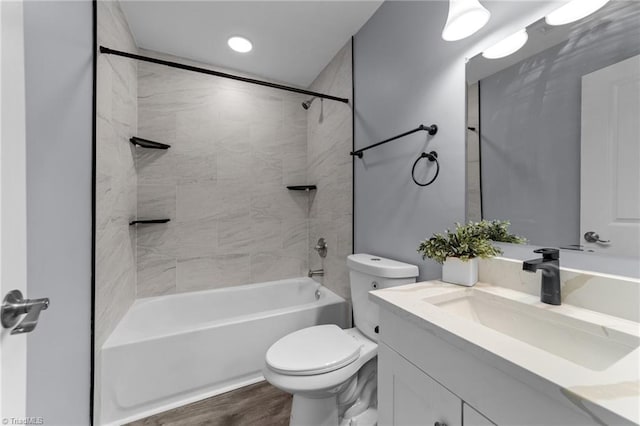 full bathroom featuring vanity, hardwood / wood-style floors, tiled shower / bath combo, and toilet